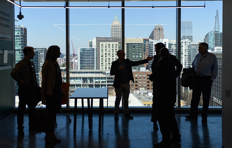 A group of silhouettes standing in front of a large window