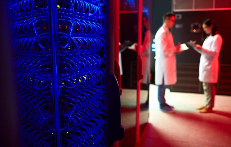 Two people in lab coats stand in a server room