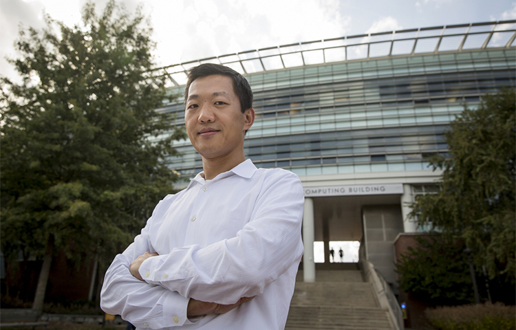 A man standing with his arms folded across his chest outside of a alrge building