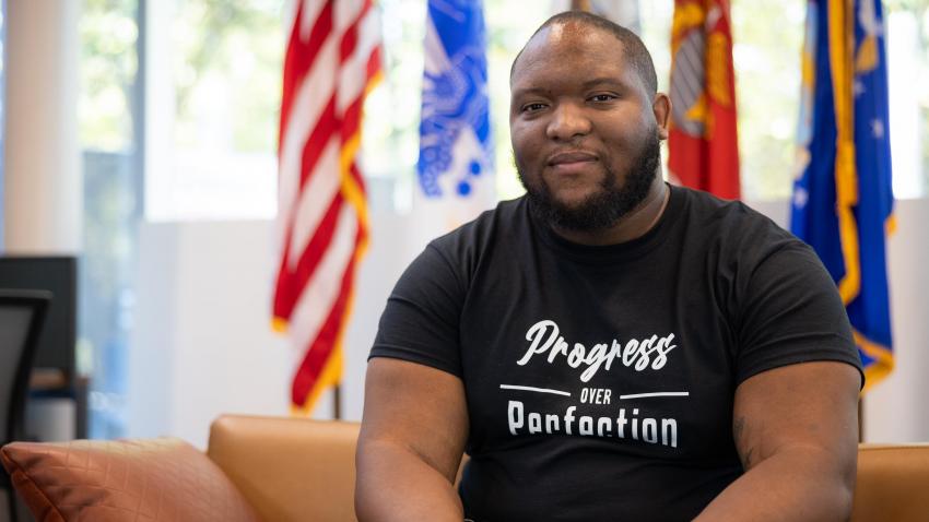 man sitting on couch with flags behind him