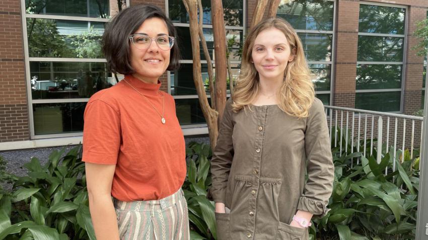 two women standing next to each other outside