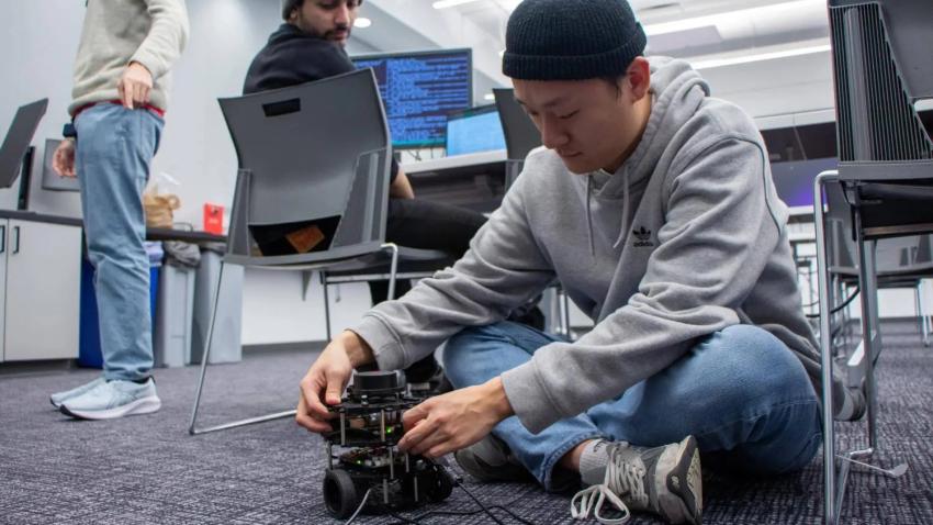 man seated on the ground works on a piece of hardware