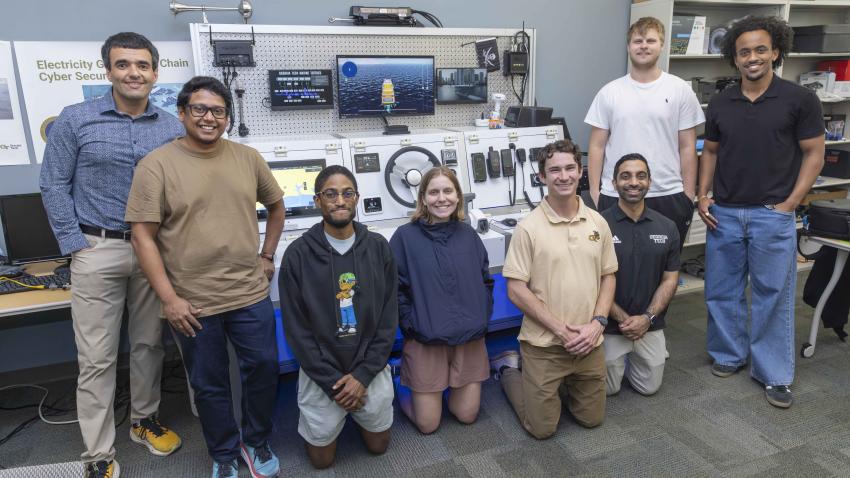A group photo of students and faculty standing around lab equipment found on a ship.