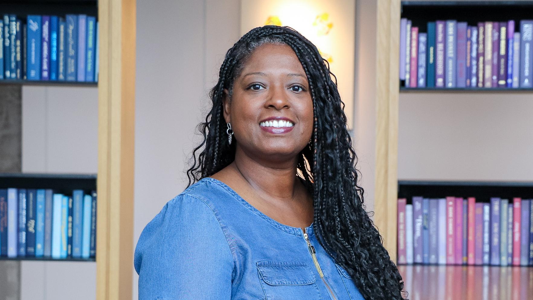 A smiling woman with long dark hair wearing a blue blouse